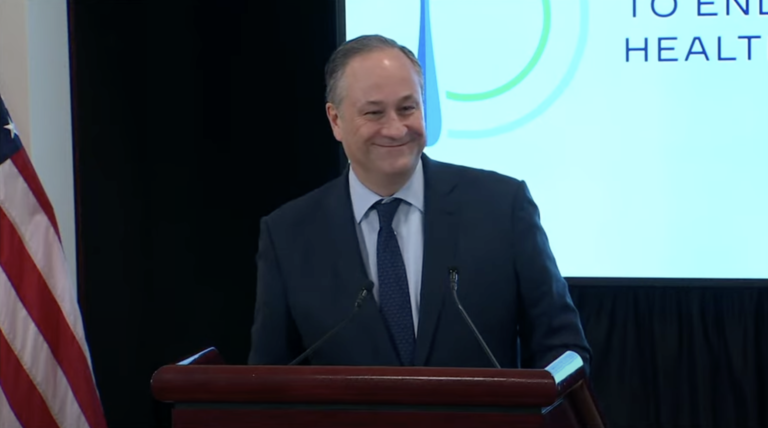 A man in suit and tie standing at a podium.